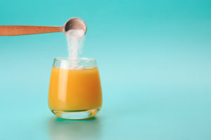 Suplemento sendo colocado no copo de suco laranja